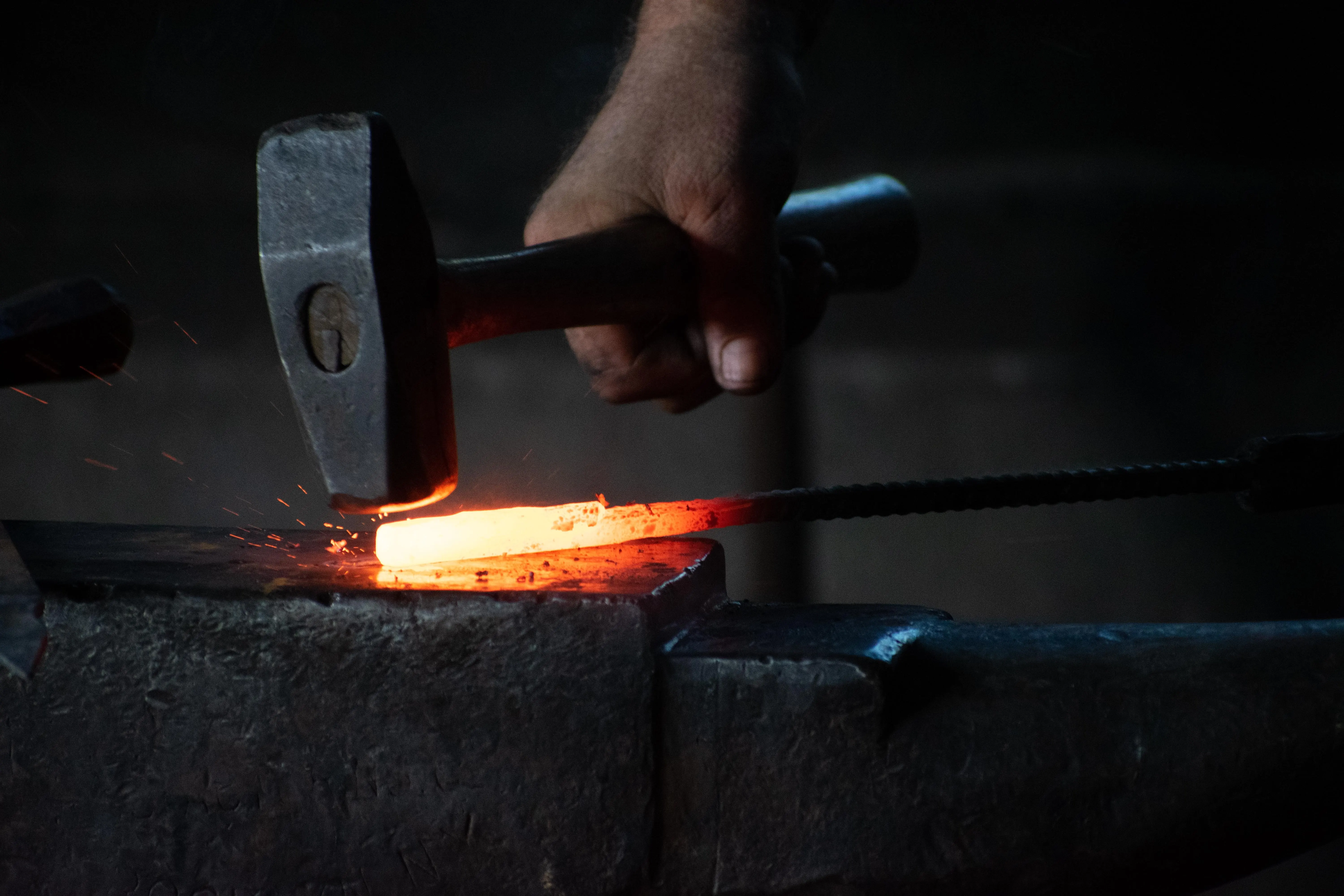 hammering a hot iron bar on anvil